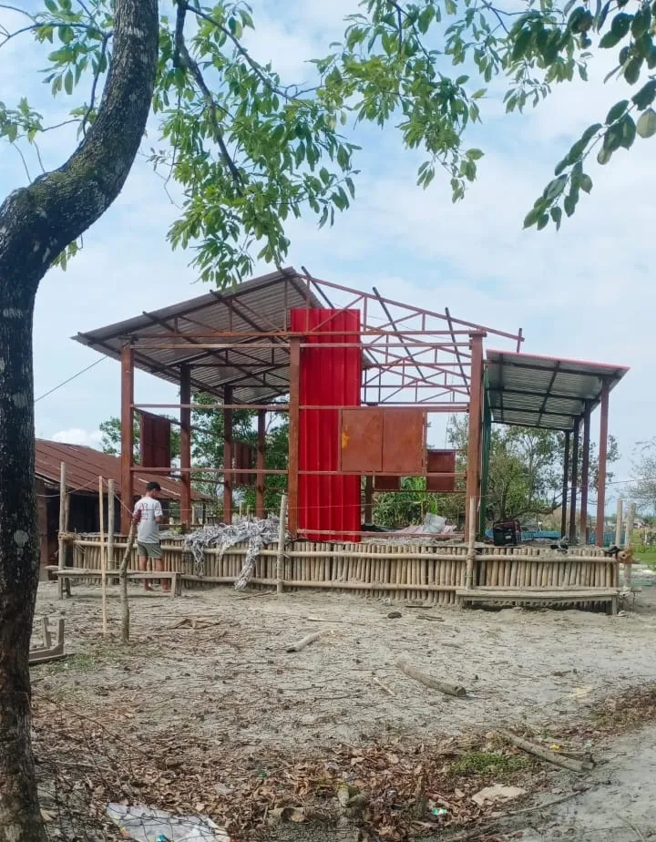 A steel-framed structure with red cladding going up